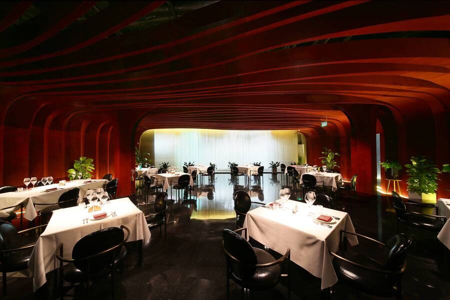 Second-floor open dining area with red velvet walls and curved ceilings creating a theatrical, futuristic atmosphere.