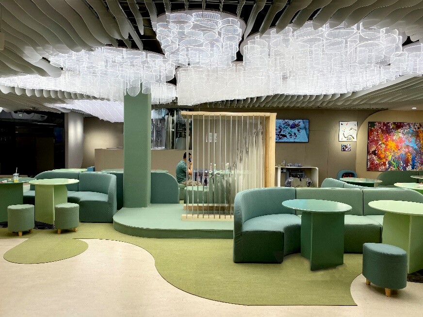 Second-floor public rest area with green soft seating and translucent acrylic tree-like lighting.