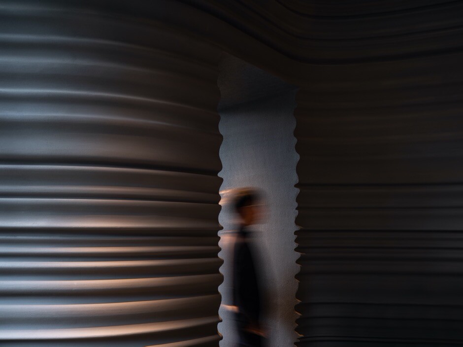 Main dining space with curved walls, greenery, tables, and lighting installation reinterpreting the relationship among Italian sculpture, food, and nature.