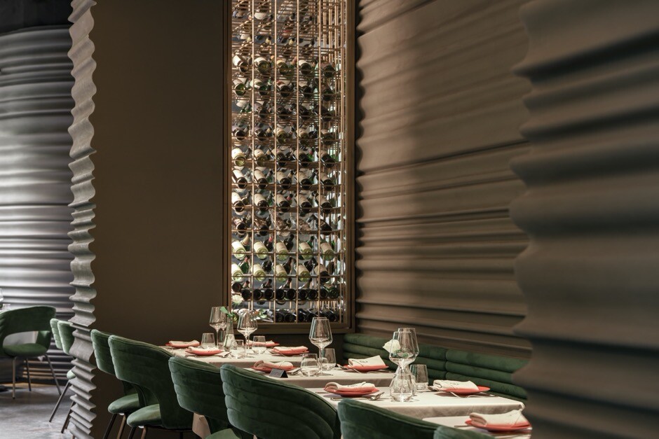 Interior dining atmosphere formed by abundant greenery, natural light, and curved walls.